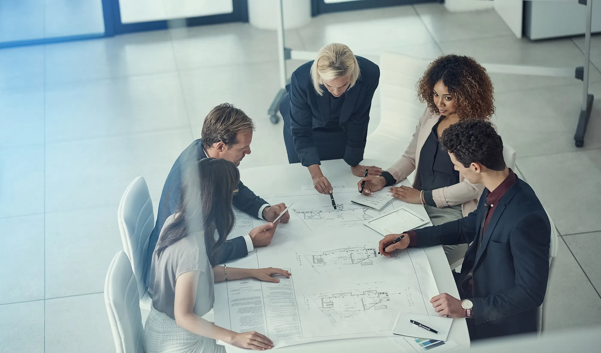 Un team è riunito a un tavolo mentre analizza alcuni fogli contenenti delle planimetrie