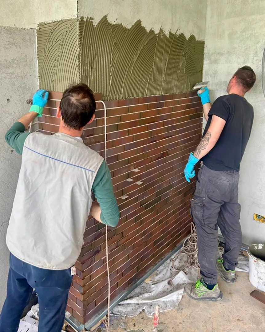 Due posatori applicano un rivestimento modulare a una parete